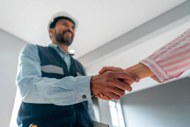 Building contractor being hired by a woman and closing the deal with a handshake - house renovation concepts