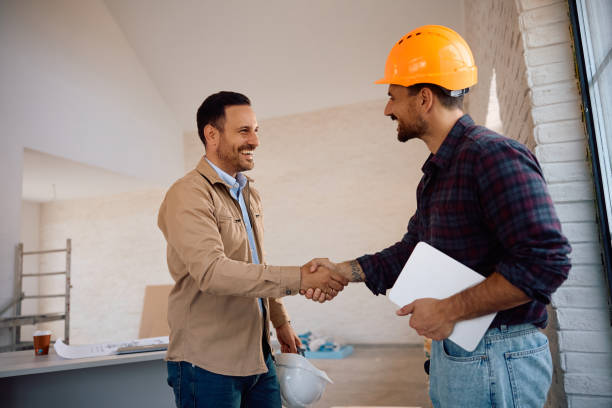 Happy worker and his clients shaking hands at constriction site. Copy space.