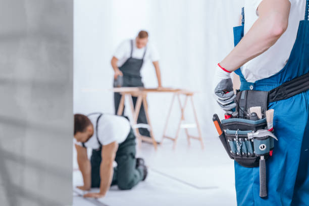Close-up of handyman with glove on hand and tool belt on blue trousers during home renovation