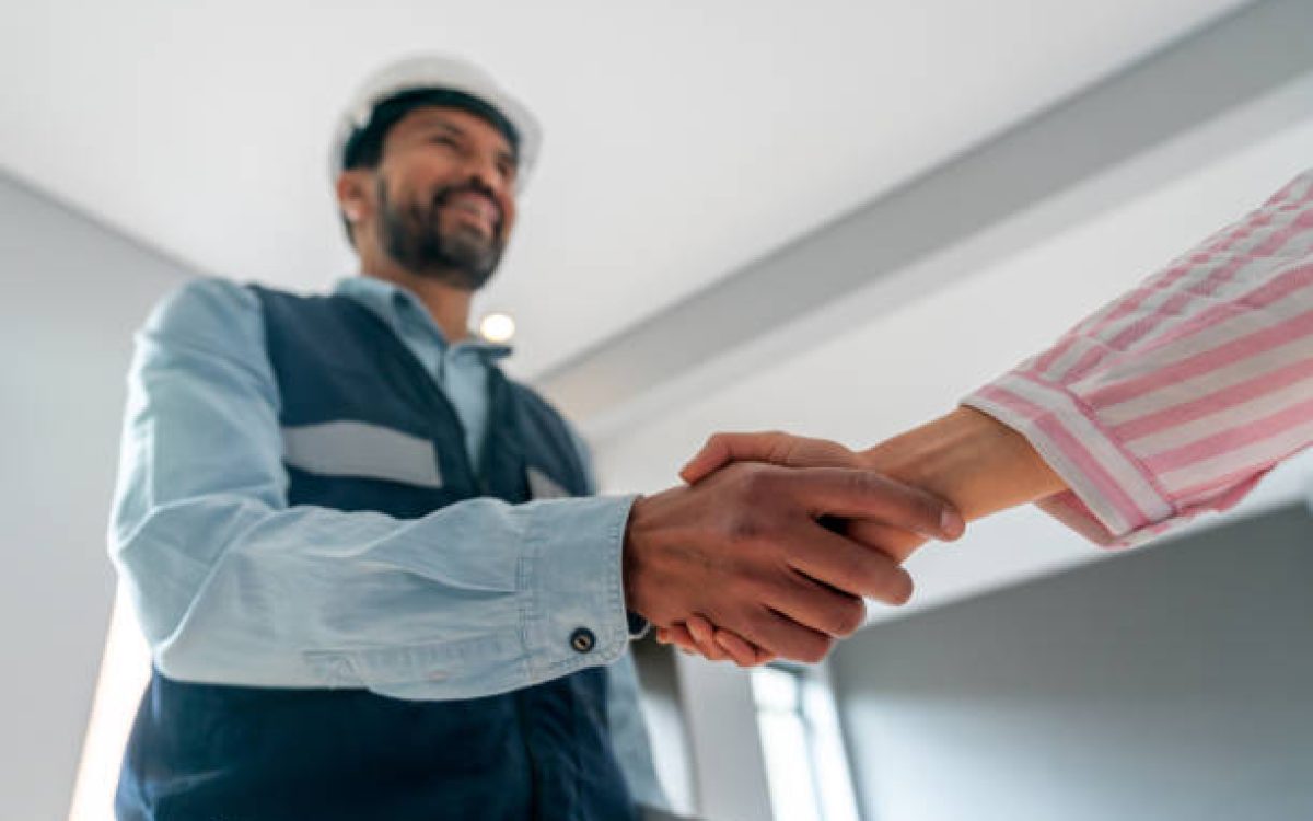Building contractor being hired by a woman and closing the deal with a handshake - house renovation concepts