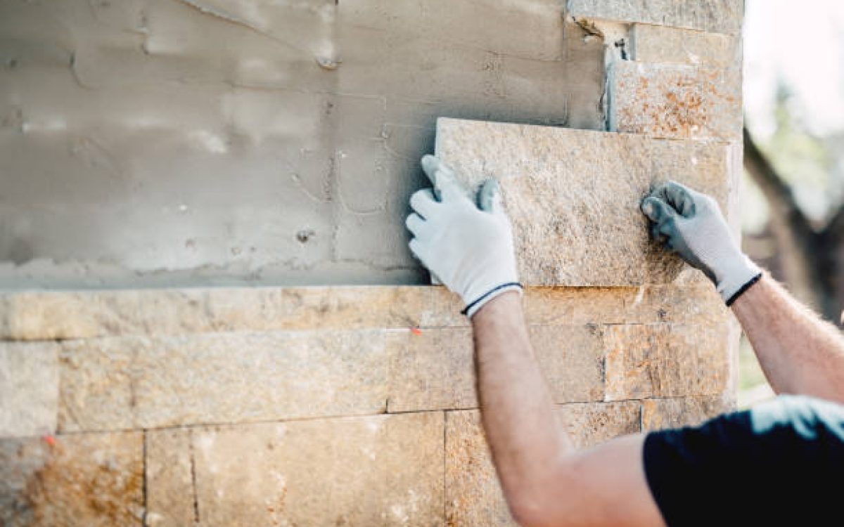 Construction worker installing stone on architectural facade of new building. details of construction industry