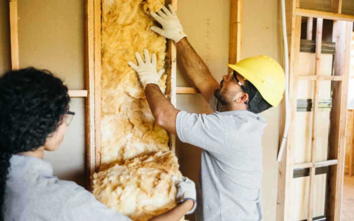 Construction workers fitting insulation in frame