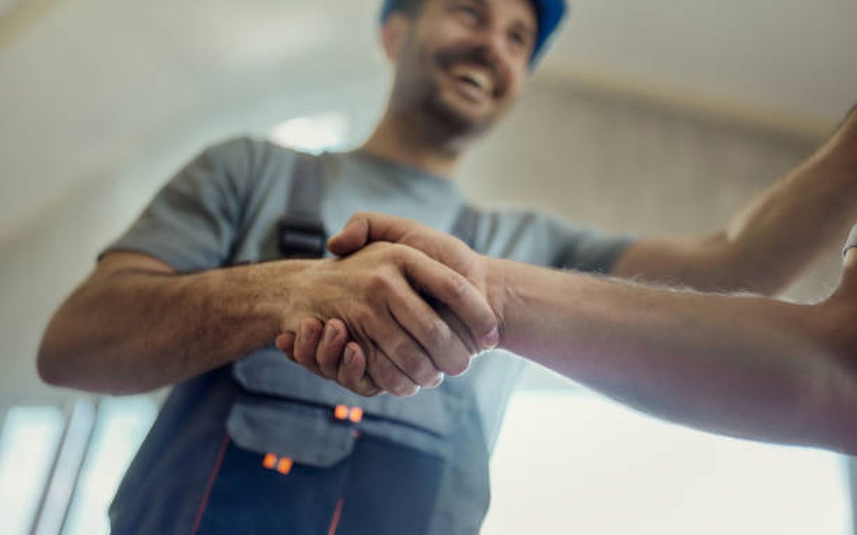 Close up of manual workers greeting with a handshake during home renovation process.