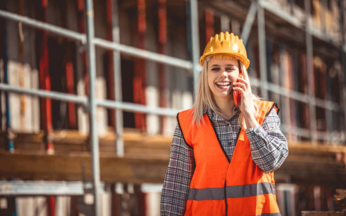 Architect woman using phone and happy on construction site in industry, planning and inspectioning