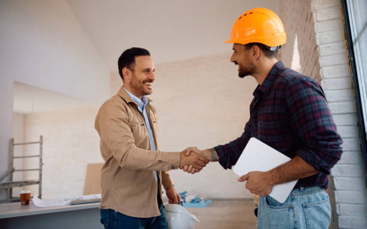 Happy worker and his clients shaking hands at constriction site. Copy space.