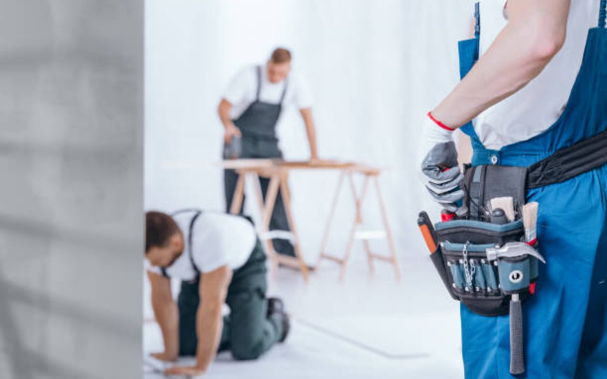 Close-up of handyman with glove on hand and tool belt on blue trousers during home renovation