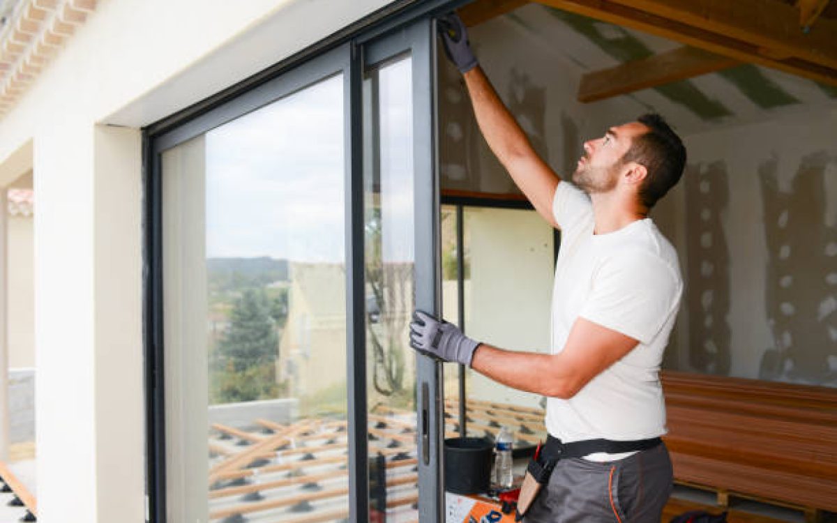 handsome young man installing bay window in a new house construction site